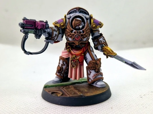 An Emperor's Children Legion Praetor painted white with golden accents holding a down pointed sword and pointing a pink gun